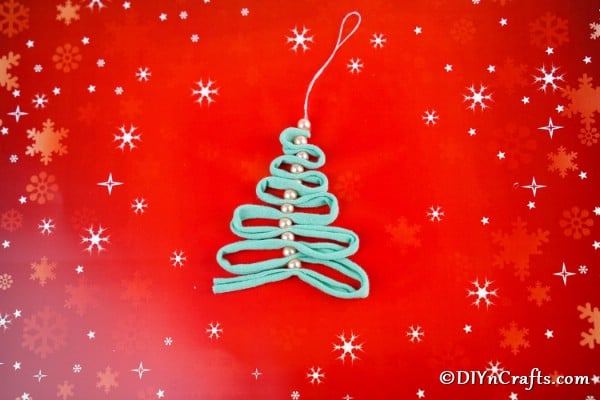 Pearl and ribbon handmade Christmas ornaments on a red holiday background