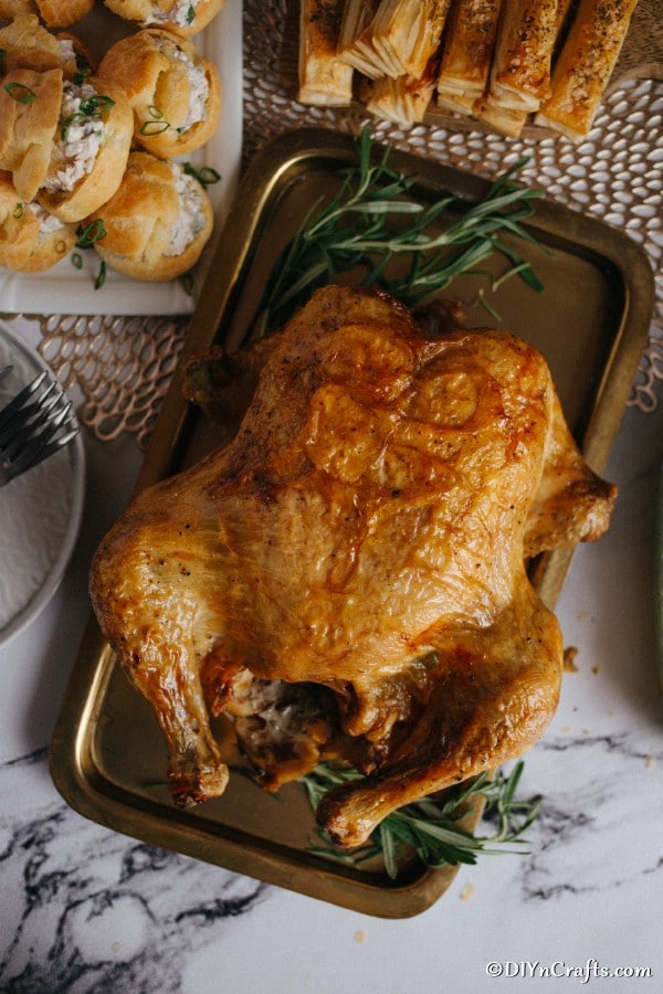 A large roasted rosemary chicken on a baking sheet