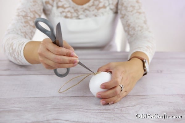 Adding the twine hanging piece to the middle of the styrofoam ball for a rustic ornament