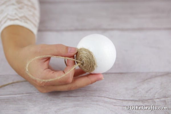 Beginning to glue twine in place on a styrofoam ball