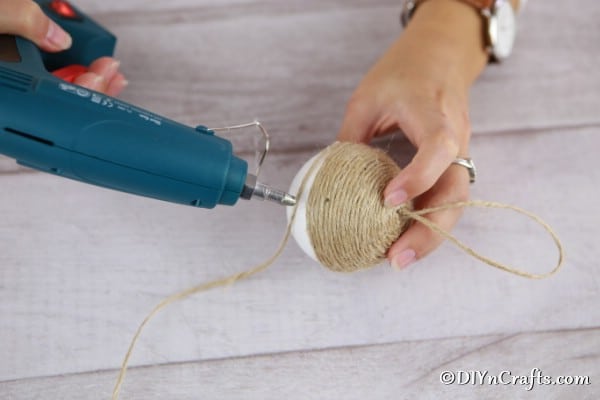 Gluing twine to the styrofoam ball for a christmas ornament