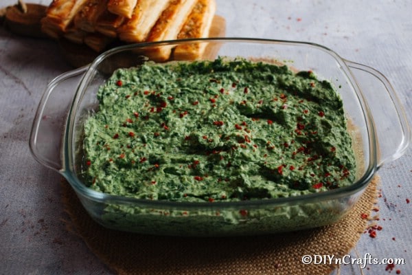 A large glass dish filled with hot spinach dip