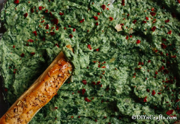 Up close image of spinach dip with a breadstick