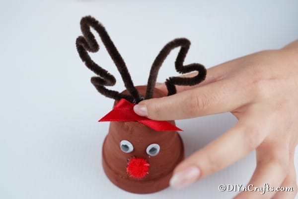 Gluing the bow and horns to the top of a reindeer christmas decor piece