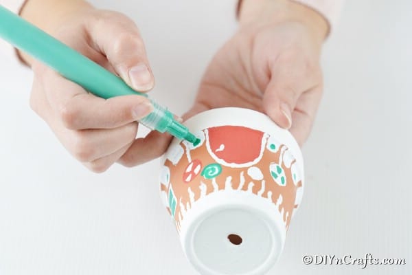 Adding decorations to the gingerbread house clay pot