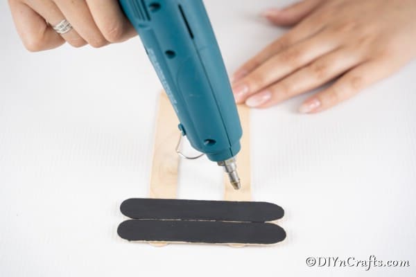 Gluing black craft sticks to the ornament