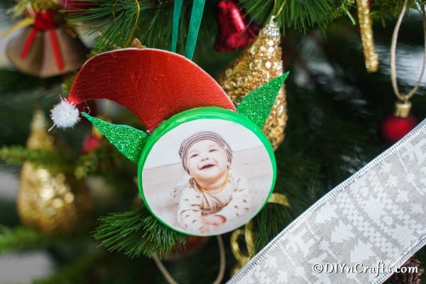 Elf photo ornament hanging on a Christmas tree