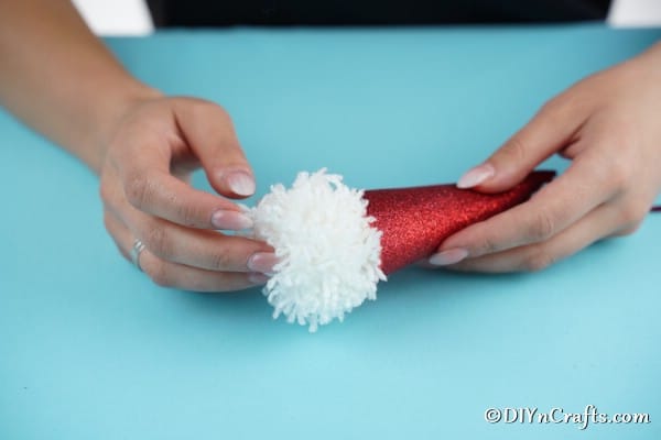 Gluing the white pom pom in place on cone to create a gnome face