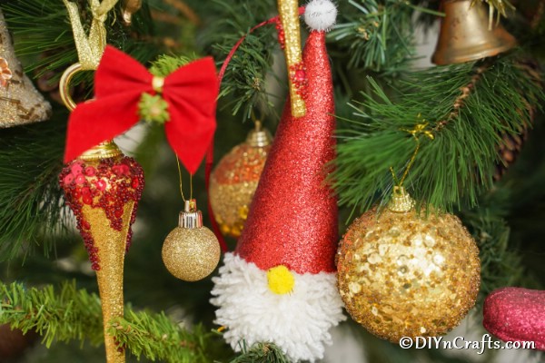 Up close picture of a gnome Christmas ornament hanging on a holiday tree