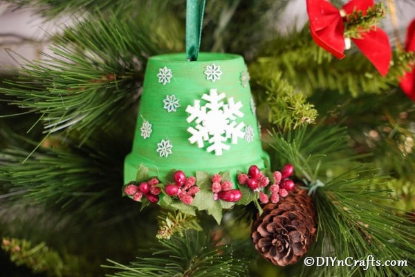 A DIY Christmas bell decoration hanging in a Christmas tree