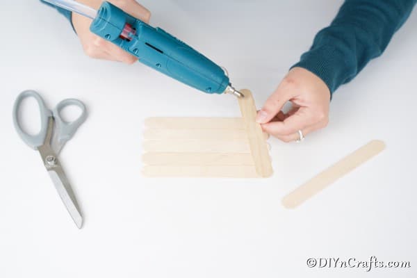 Gluing craft sticks together for a gingerbread house ornament