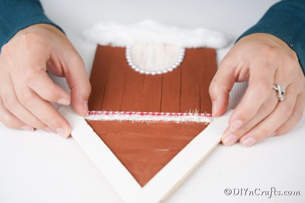 Adding ribbon to the roofline of the gingerbread house craft