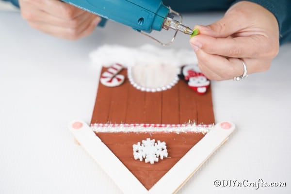 Gluing embellishments to the gingerbread house ornament craft