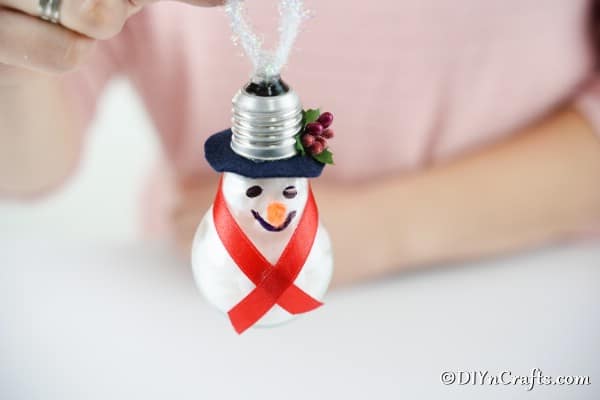 Adding a piece of twine to the back of a lightbulb snowman ornament