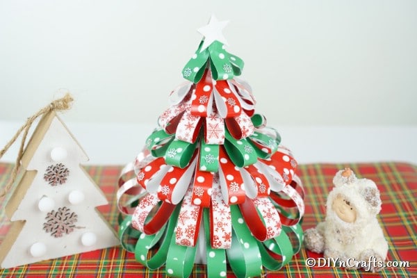 A paper strip Christmas tree displayed next to other holiday decor pieces