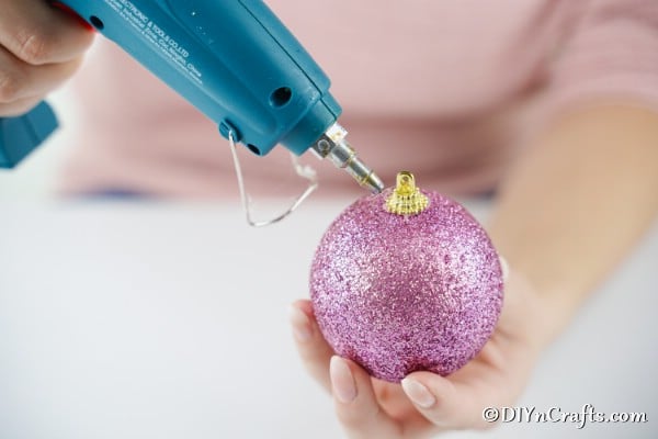 Adding glue to the top of a Christmas ball to create icing