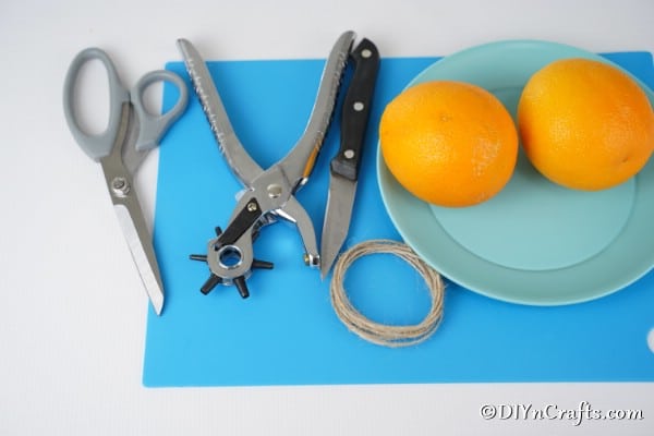 Supplies for making orange peel garland laying on a blue table mat