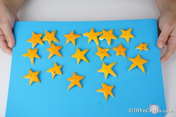 A tray of orange stars with holes ready to be threaded onto a garland