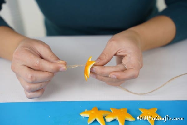 Threading orange stars onto a thread for a simple Christmas garland
