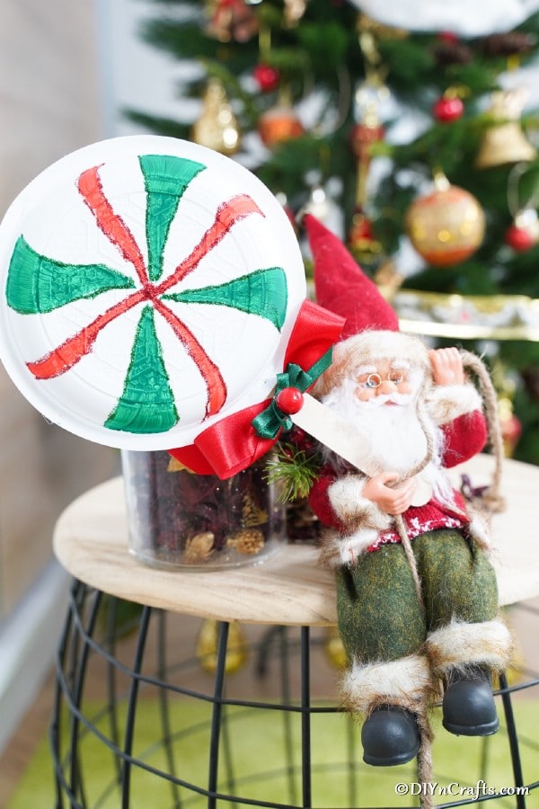 Giant lollipops on a stool with toy Santa in front of the Christmas tree