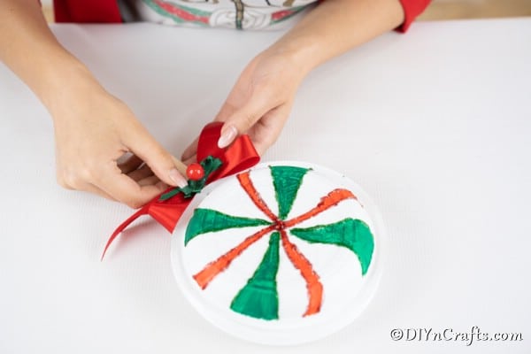 Gluing the bow in place on the paper plate giant lollipops decoration
