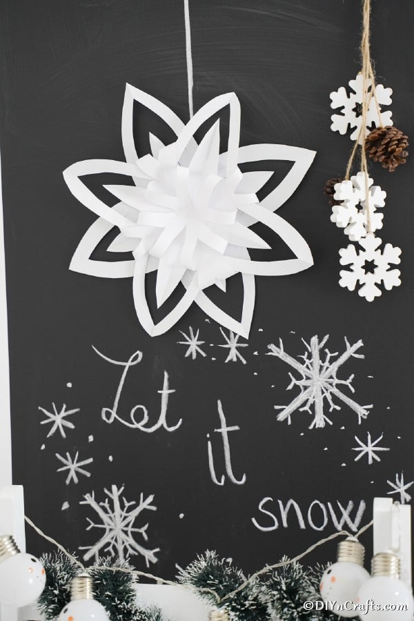 3d snowflake paper ornaments in front of chalkboard sign