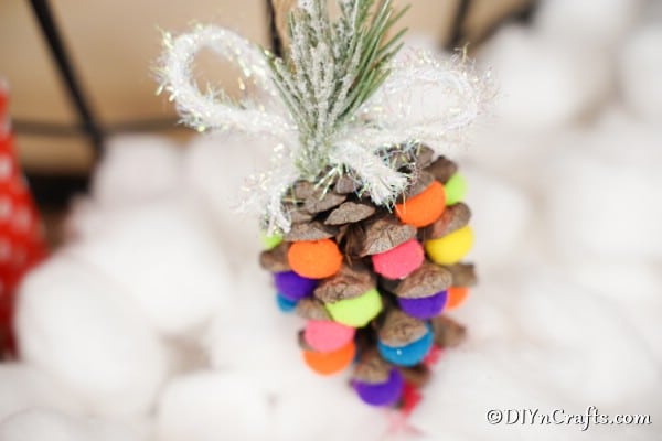 Up close picture of a colorful pinecone ornament against white cotton balls