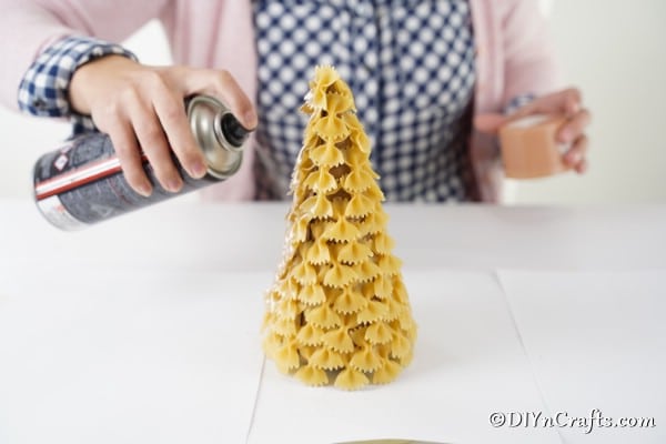 Spray painting a pasta Christmas tree with gold paint