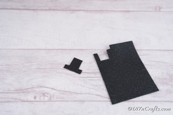 Cutting a black hat out of foam board to glue onto the Christmas candles