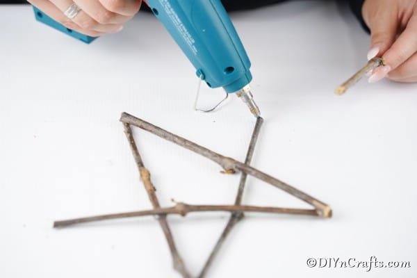 Gluing twigs together to make a rustic star ornament