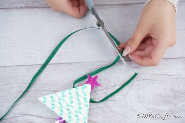 Adding a ribbon to the top of the paper Christmas tree craft