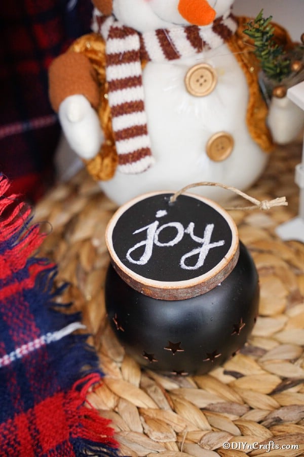 A wood slice chalkboard ornament displayed on top of a tealight candle warmer