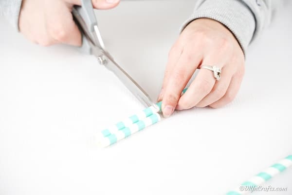 Cutting teal striped paper straws 