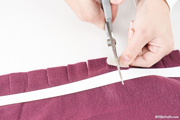 Couper une fente dans la frange de tissu pour faire passer le tissu à travers
