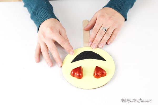 Attaching craft stick to emoji face
