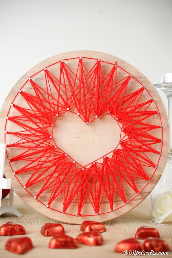 Round wood piece with red heart string art