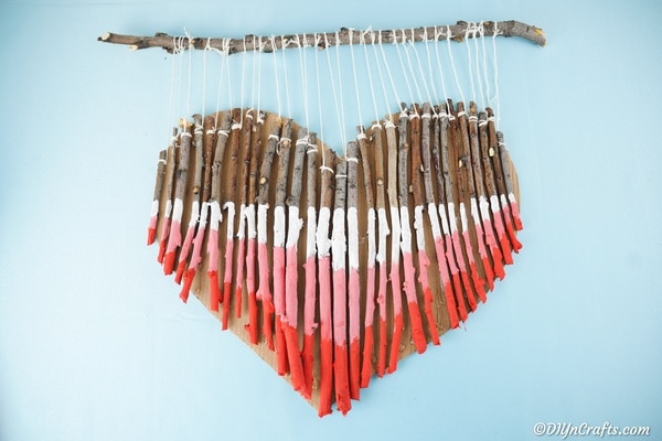 Painted twig wooden heart wall art on blue wall