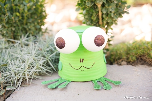Flower pot garden frog sitting on a sidewalk
