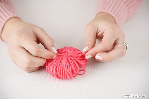 Tying yarn in center of pom pom
