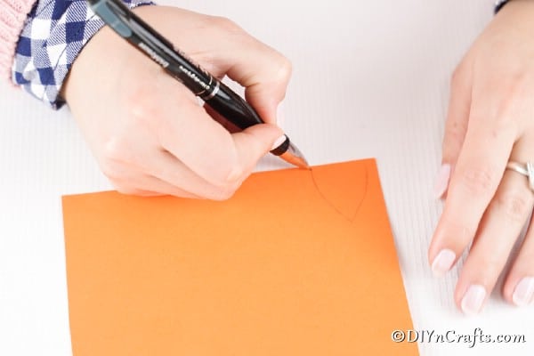 Drawing ears and a tail on orange paper for fox egg