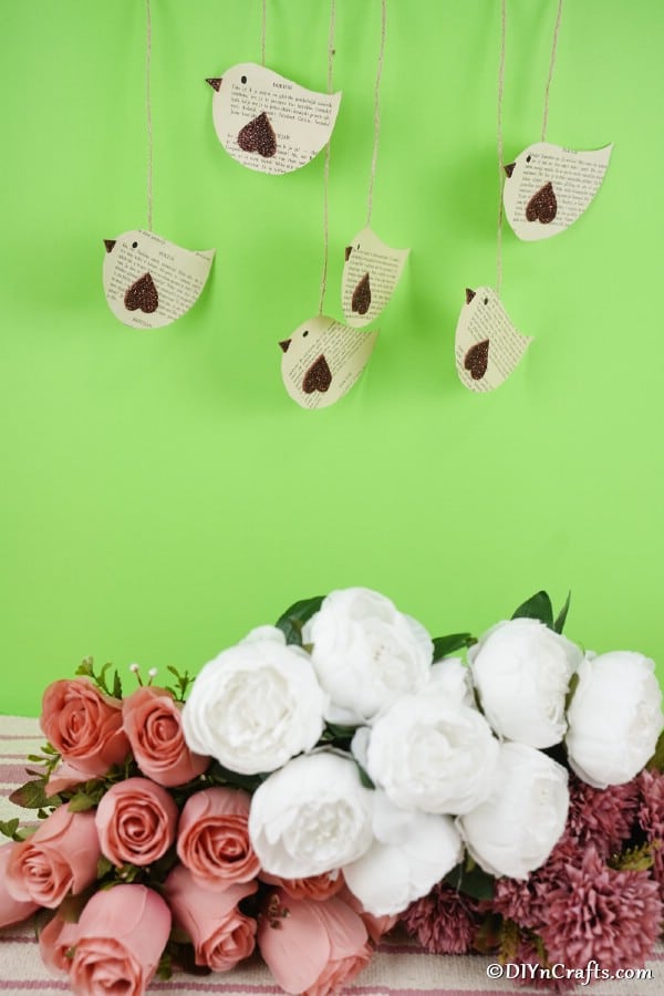 Paper birds hanging against green wall