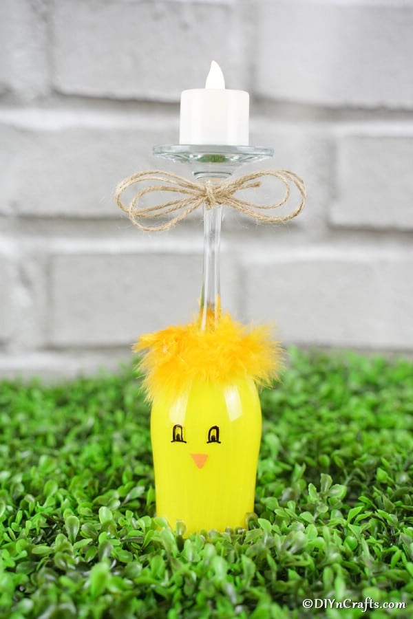 Yellow wine glass chicken on a patch of fake grass