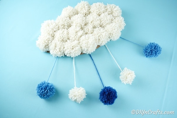 Cloud pom pom craft on blue surface