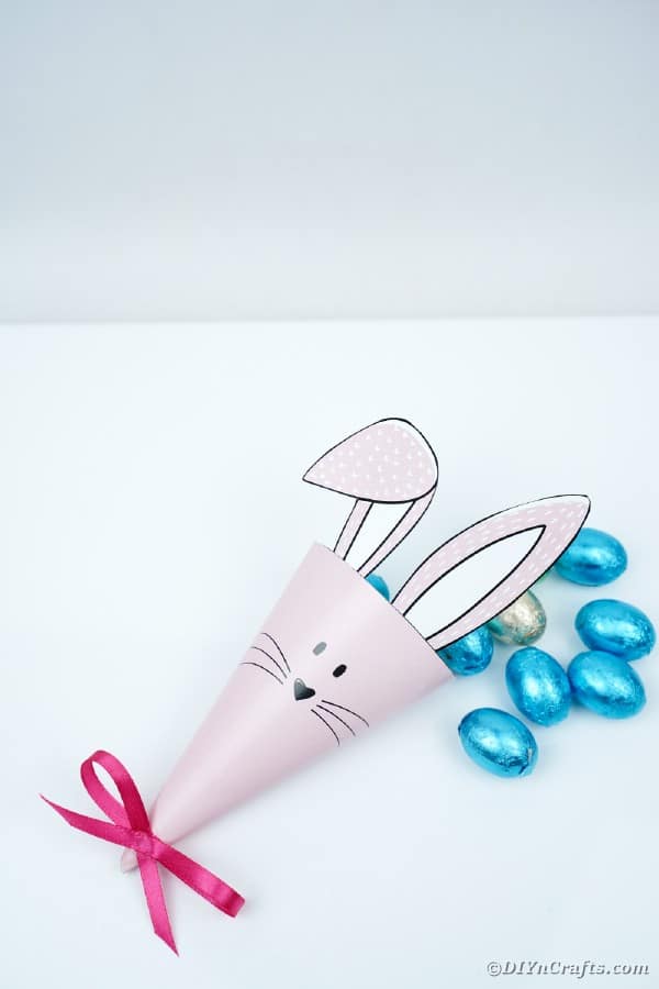 Paper bunny cone on white table with blue candy