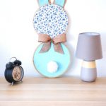 Fabric bunny wall art on table by lamp