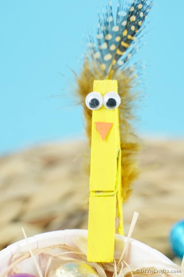 Yellow clothespin bird clipped to cup