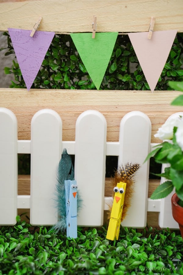 Clothespin birds against mini white fence
