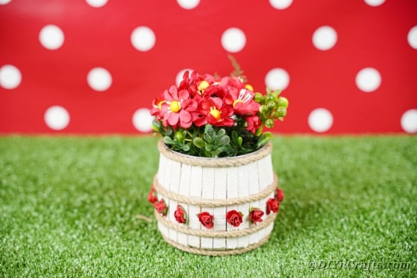 Clothespin tin can organizer on grass with red polka dot background