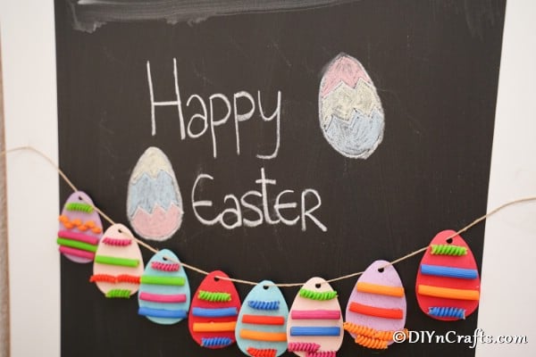 Painted pasta Easter egg garland hanging on chalkboard