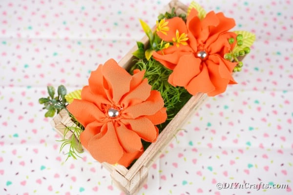 Wood box of orange flowers on patterned fabric surface